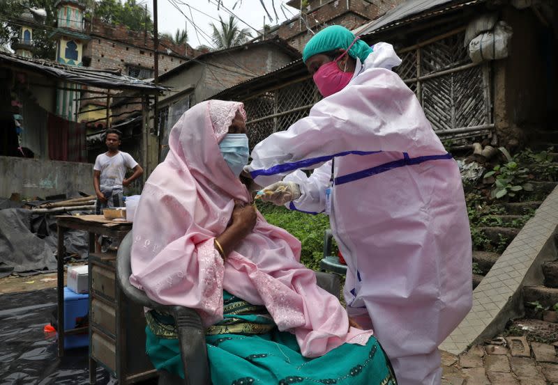 A villager receives a dose of COVISHIELD vaccine during a door-to-door vaccination and testing drive at Uttar Batora Island