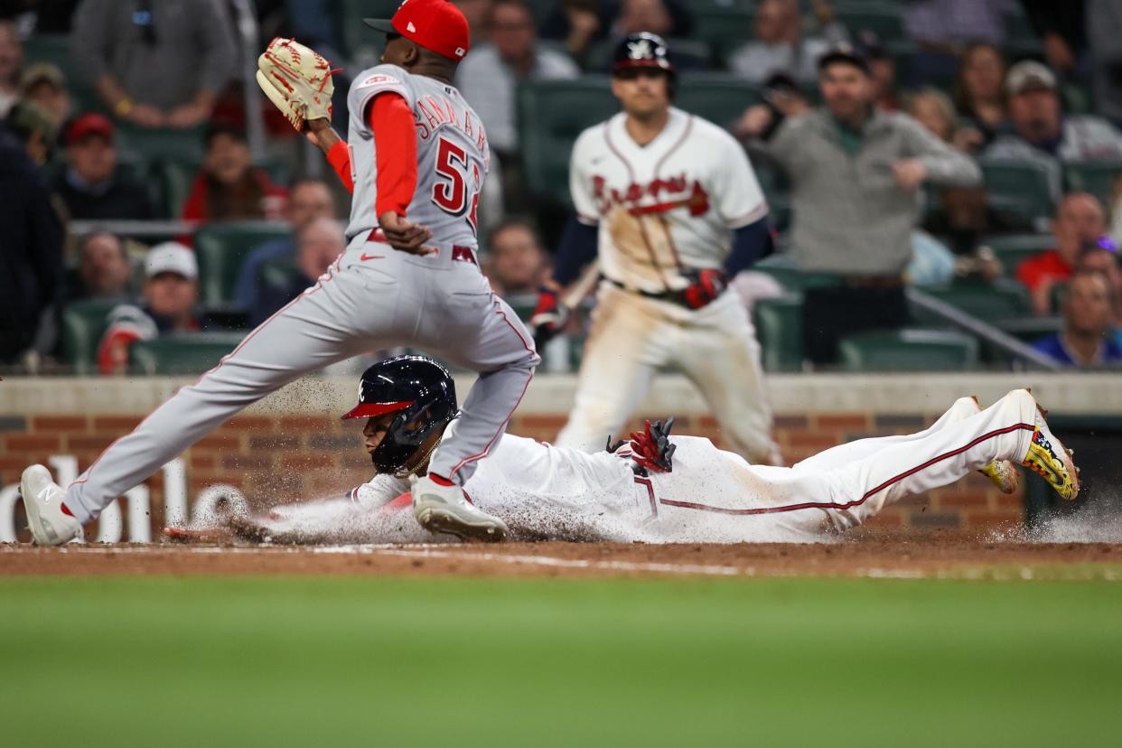 Atlanta Braves shortstop Orlando Arcia (11) slides past Cincinnati Reds relief pitcher Reiver Sanmartin (52) to score a run in the seventh inning at Truist Park.  Brett Davis-USA TODAY Sports