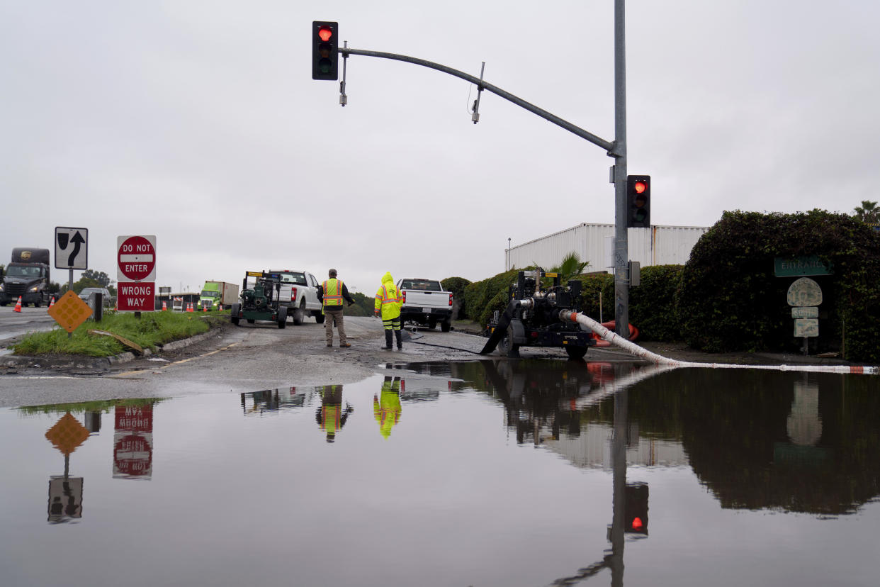 Workers prepare to pump out a flooded street.