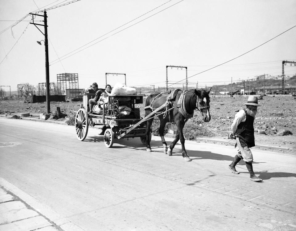 FILE - In this Oct. 11, 1945, file photo, an elderly bearded Japanese leads a horse pulling a wagon loaded with other members of the family and their household goods past the wreckage of buildings on the outskirts of Tokyo as people return to their home after having evacuated during U.S. air raids on the Japanese capital. The bombs stopped falling 75 years ago, but it is entirely possible - crucial even, some argue - to view the region’s world-beating economies, its massive cultural and political reach and its bitter trade, territory and history disputes all through a single prism: Japan’s aggression in the Pacific during World War II. (AP Photo/Max Desfor, File)