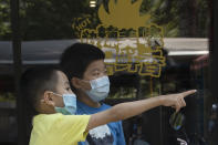Children wearing masks to curb the spread of the new coronavirus chat outside a restaurant in Beijing on Friday, June 19, 2020. China declared a fresh outbreak in Beijing under control after numbers for new cases stabilized as hundreds of thousands are tested. (AP Photo/Ng Han Guan)