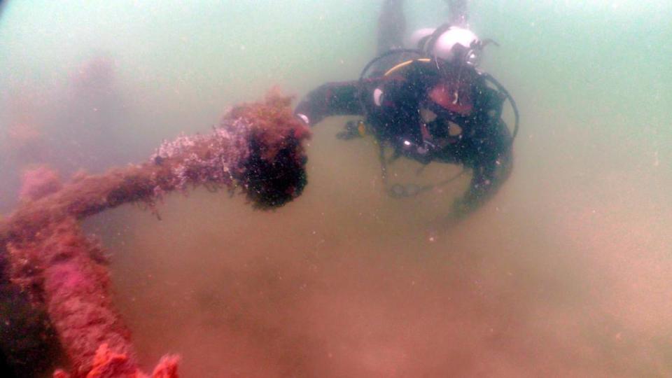 Um mergulhador observa uma estrutura subaquática nas águas turvas do Golfo.