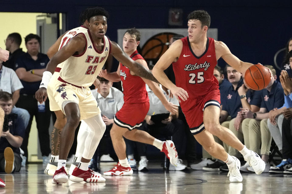 Liberty forward Zach Cleveland (25) drives to the basket as Florida Atlantic guard Brandon Weatherspoon (23) defends during the second half of an NCAA college basketball game, Thursday, Nov. 30, 2023, in Boca Raton, Fla. (AP Photo/Lynne Sladky)