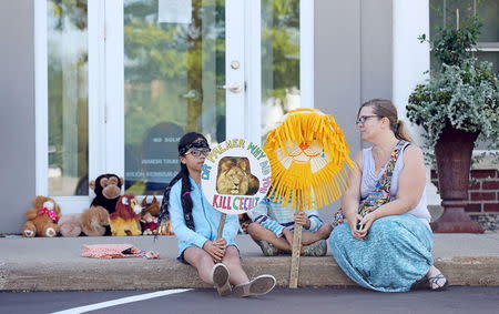 Hayley Hoppe (R) sits with her daughters Piper, 10, (L) and Paisley, 8, (C), in front of the doorway of River Bluff Dental clinic in protest against the killing of a famous lion in Zimbabwe, in Bloomington, Minnesota July 29, 2015. REUTERS/Eric Miller