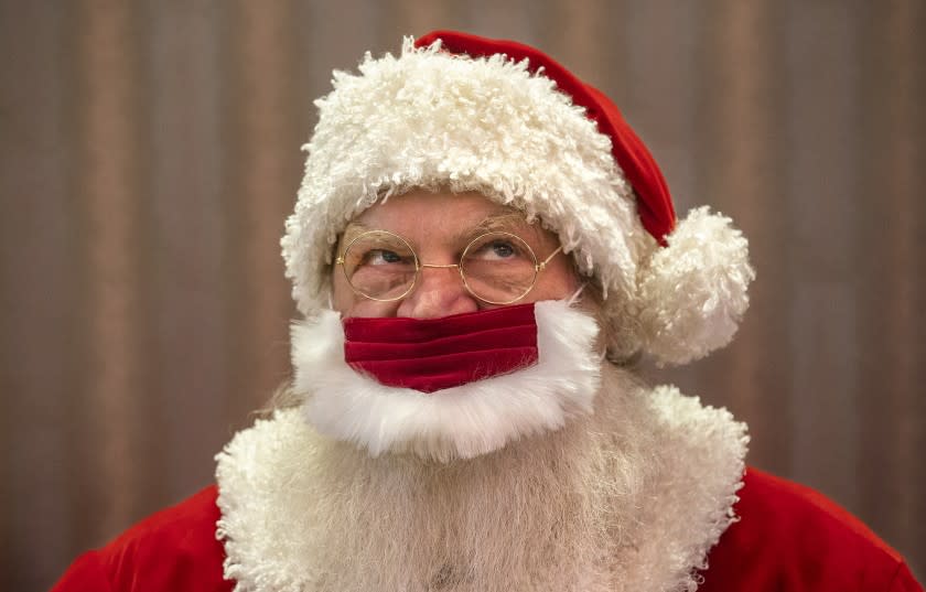 CANOGA PARK, CA - DECEMBER 02: Santa Claus, Jeffrey Fast, wears a protective mask against the coronavirus, while waiting for children to arrive for a photo and meeting with him at the Westfield Topanga Mall in Canoga Park. He was sitting in an enclosed space to guarantee a safe distance between him and the children. (Mel Melcon / Los Angeles Times)