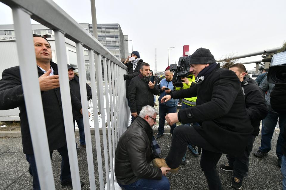 Parliamentary deputy of the oppositional Hungarian Socialist Party MSZP Zsolt Molnar, left, watches Democratic Coalition's (DK) deputy Zsolt Greczy, right, receiving help to climb the fence of the headquarters of the public broadcaster MTVA in Budapest, Hungary, Monday, Dec. 17, 2018. Oppositional lawmakers protest against the amendments to the labour code adopted on Dec. 12, and insist to read out their demands live in the public media. (Zsolt Szigetvary/MTI via AP)