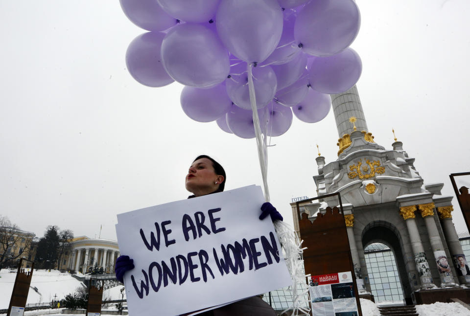 En esta imagen de archivo, una mujer sostiene globos y un cartel para conmemorar el Día Internacional de la Mujer, en Kiev, Ucrania, el 8 de marzo de 2018. Mujeres de todo el mundo exigirán igualdad salarial, derechos reproductivos, educación, justicia y otras necesidades esenciales durante las manifestaciones para conmemorar el Día Internacional de la Mujer el 8 de marzo. (AP Foto/Efrem Lukatsky, archivo)