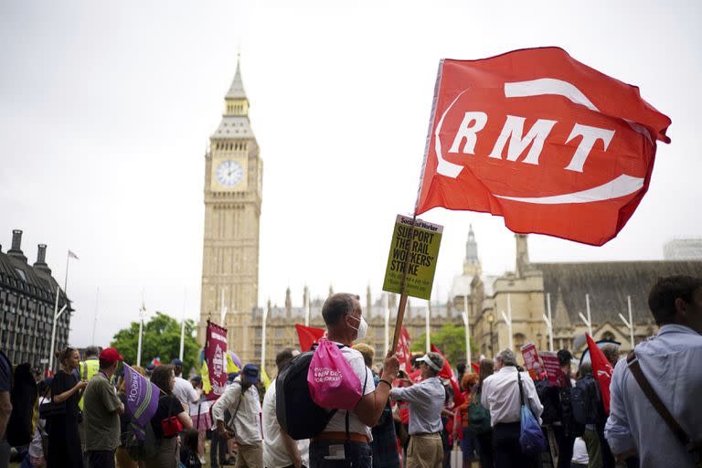 Varias personas sostienen letreros durante una protesta para exigir acciones en torno al aumento del costo de la vida en Gran Bretaña, el sábado 18 de junio de 2022, en Londres. (Yui Mok/PA vía AP)