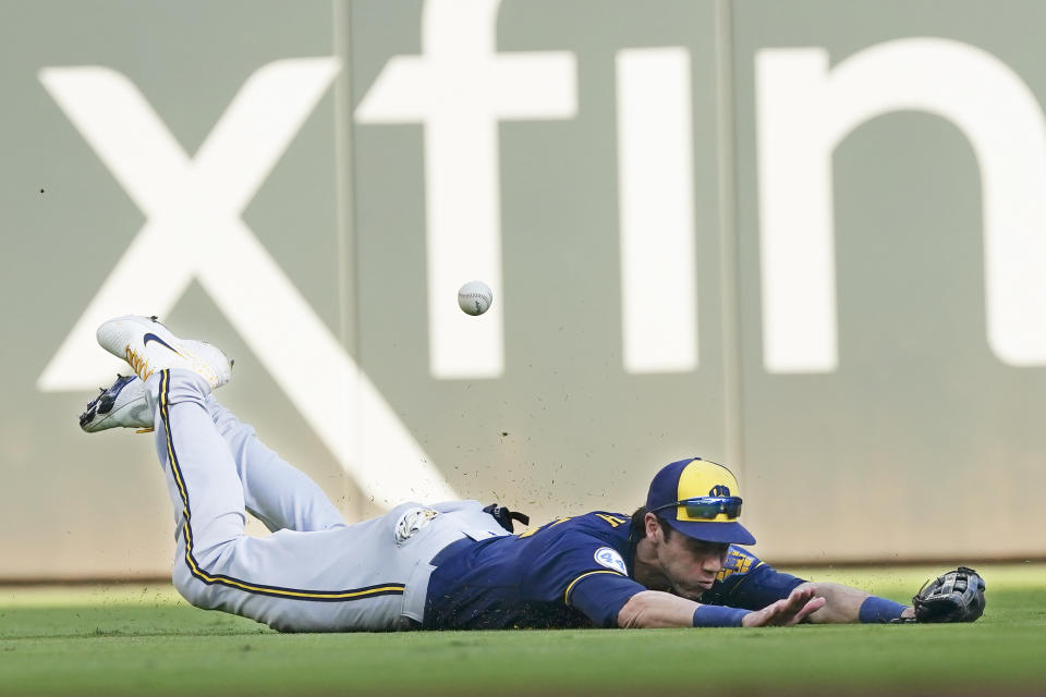 Milwaukee Brewers left fielder Christian Yelich (22) dives the for the ball hit by Atlanta Braves' Adam Duvall during the second inning of Game 4 of a baseball National League Division Series, Tuesday, Oct. 12, 2021, in Atlanta. Duvall made it to first base on the hit.(AP Photo/John Bazemore)