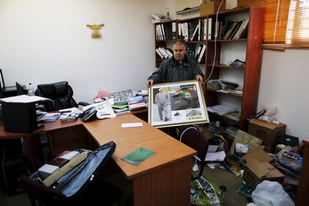 A man carries a photo inside the offices of the The Islamic Movement northern branch in Israel after Israel outlawed the Movement today in Umm al-Faham, northern Israel, November 17, 2015. . REUTERS/Ammar Awad