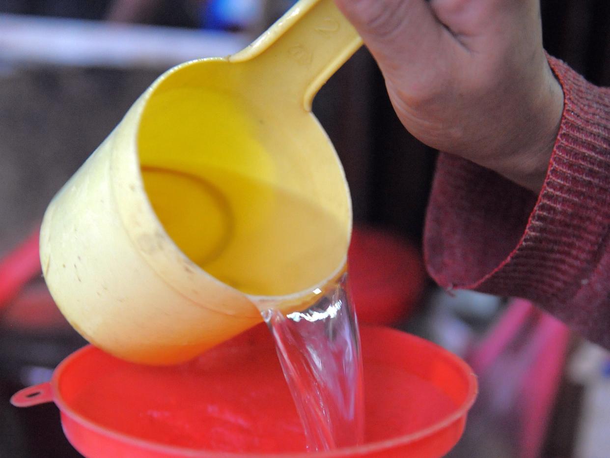 A Cambodian woman decants rice wine into a water bottle for sale in Phnom Penh (AFP via Getty Images)