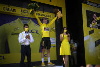 Belgium's Wout Van Aert, wearing the overall leader's yellow jersey celebrates on the podium after winning the fourth stage of the Tour de France cycling race over 171.5 kilometers (106.6 miles) with start in Dunkerque and finish in Calais, France, Tuesday, July 5, 2022. (AP Photo/Daniel Cole)