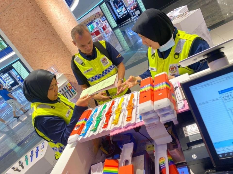 Home Ministry officers are pictured with seized Swatch watches at Southkey mall in Johor. — Picture courtesy of Swatch