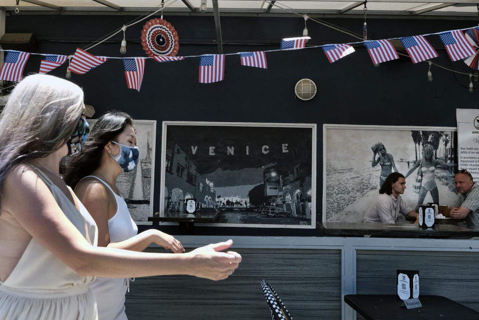 Pedestrians wearing masks walk past a Venice beach restaurant on Friday, July 3, 2020 in Los Angeles. California's governor is urging people to wear masks and skip Fourth of July family gatherings as the state's coronavirus tally rises. But Gov. Gavin Newsom on Thursday said he'd rely on people using common sense rather than strict enforcement of the face-covering order. Rates of COVID-19 infections and hospitalizations have soared in the past two weeks after falling last month. (AP Photo/Richard Vogel)