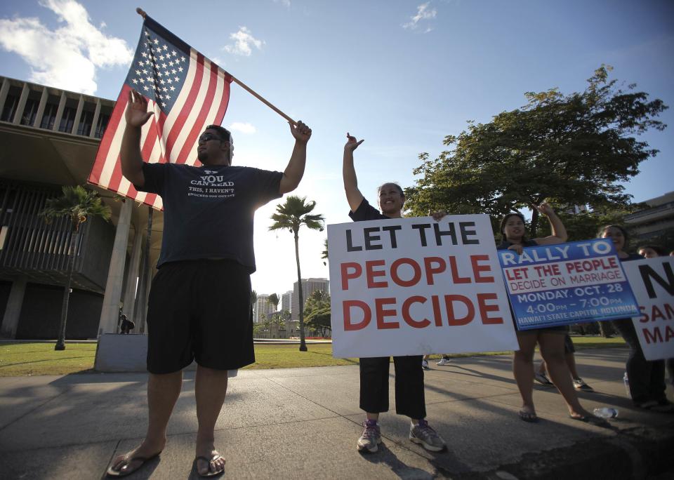 Abraham Tui and his wife Anna wave to cars at a rally against same sex marriage at the Hawaii State Capital in Honolulu