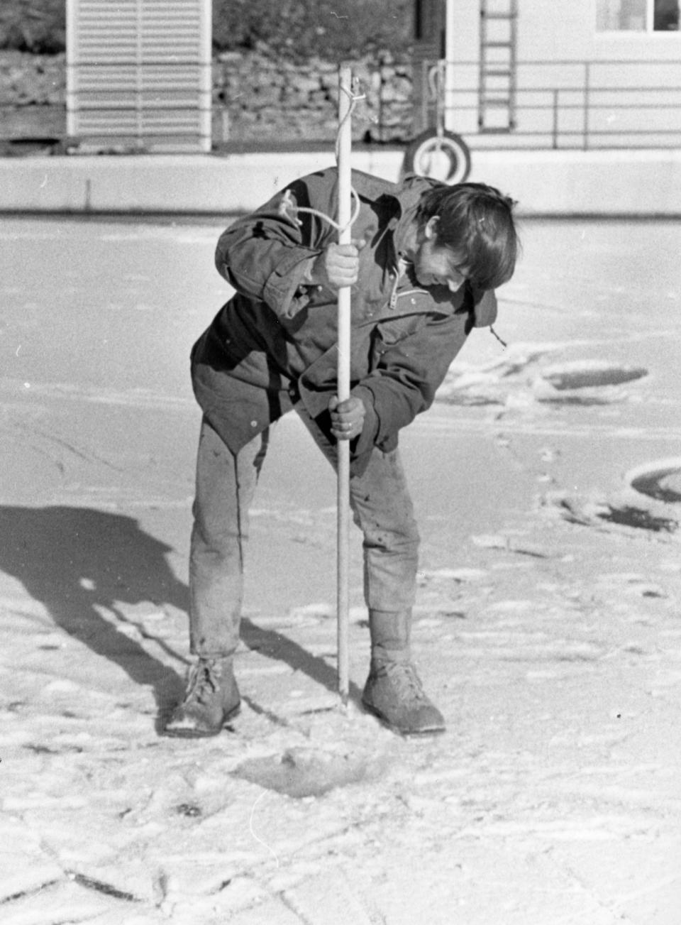 Dr. David Etnier chisels a hole in ice for ice-fishing on Feb. 13, 1977.