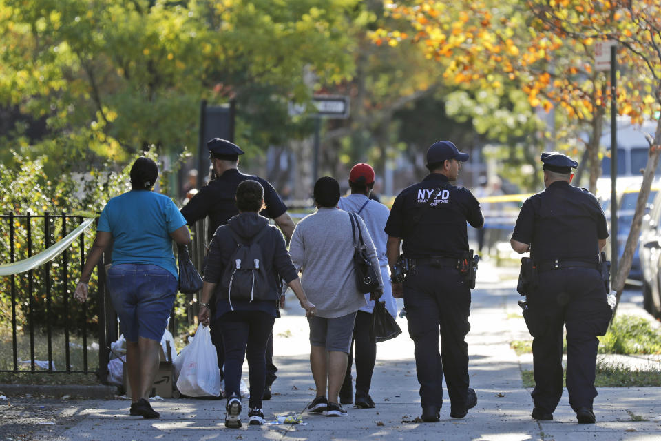 Police officers escort residents through police tape near the scene of a fatal shooting of a police officer in the Bronx borough of New York, Sunday, Sept. 29, 2019. (AP Photo/Seth Wenig)