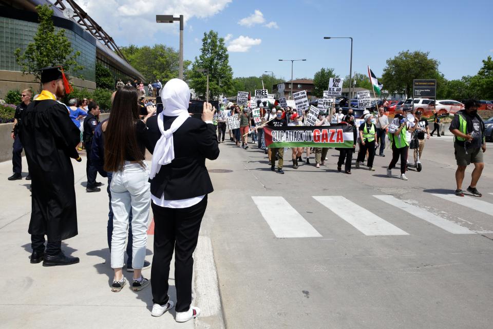Protesters pass in front of Carver-Hawkeye Arena as the College of Engineering commencement ceremony lets out Sunday, May 12, 2024 in Iowa City, Iowa.