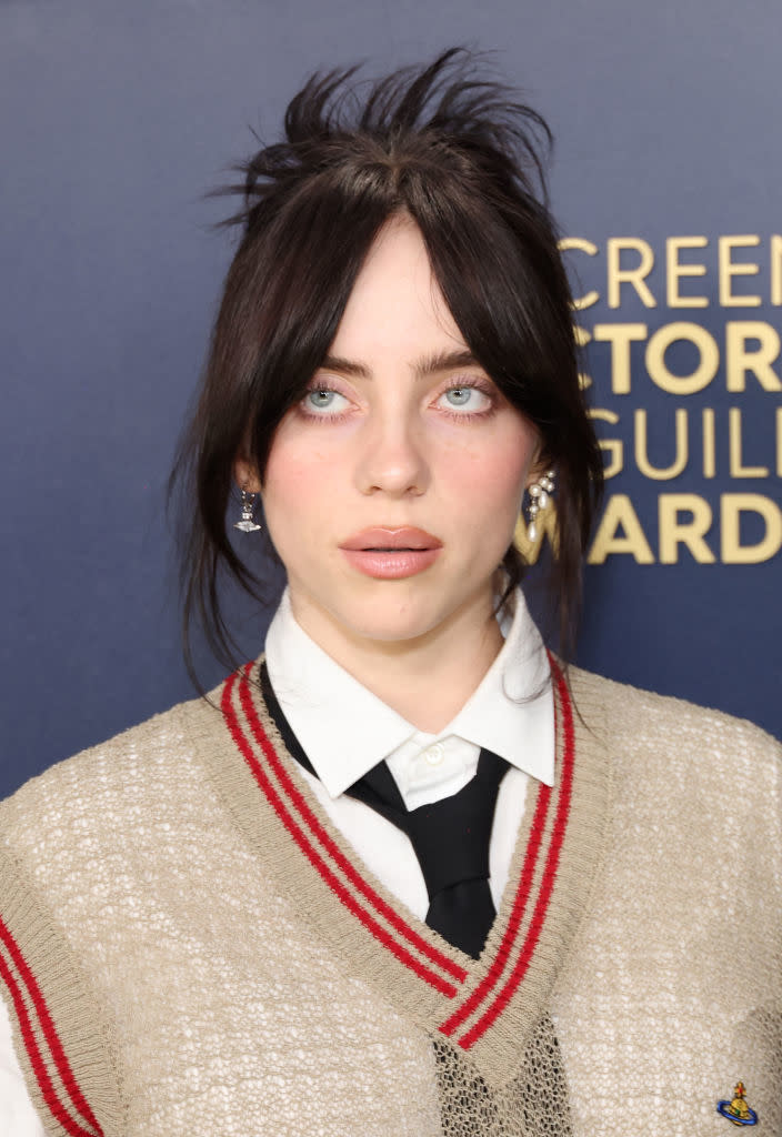 Billie with buttoned shirt and beaded vest poses at event