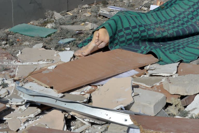 Un cadáver yace en el suelo frente a un edificio del Instituto Regional de Administración Pública de Kharkiv dañado por los bombardeos en Kharkiv el 18 de marzo de 2022, en medio de la actual invasión rusa de Ucrania.