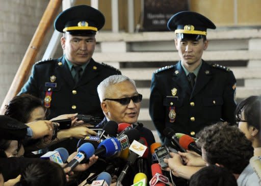 A candidate (C) is watched by security while being interviewed about the Mongolian parliamentary elections at the electoral commission in Ulan Bator, on June 29. Mongolians voted to elect a new parliament tasked with distributing the spoils of a mining boom that has brought rapid growth but also rising inequality in the resource-rich nation