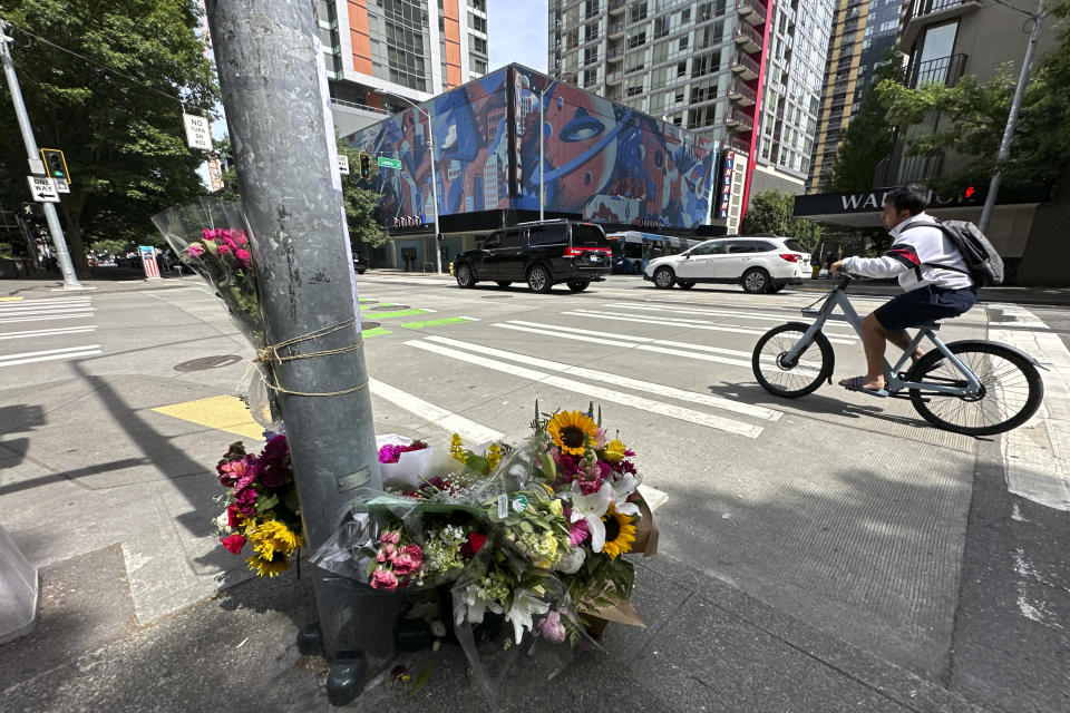 A cyclist rides past a memorial for Eina Kwon in Seattle on Friday, June 16, 2023. A pregnant woman who was killed in what appears to have been a random shooting in downtown Seattle this week has been identified as Eina Kwon, the owner of a sushi restaurant near the city's famed Pike Place Market. (AP Photo/Manuel Valdes)