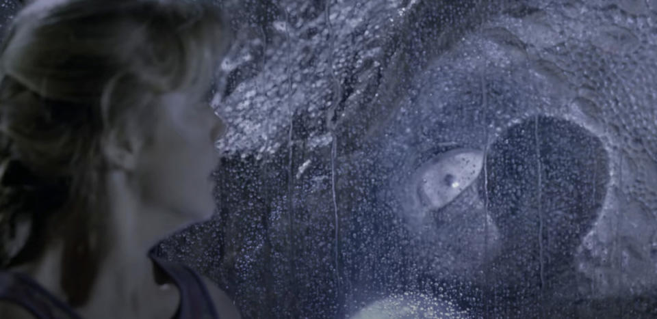 Laura Dern's character, Dr. Ellie Sattler, looks at a T. rex through a rain-soaked window in a scene from "Jurassic Park."