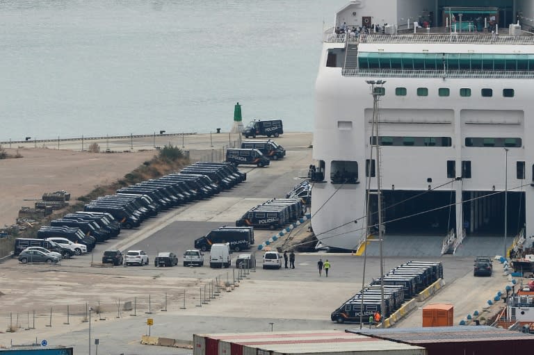 Police vans are parked next to a ship moored to the dock of Barcelona's harbour to house police reinforcements