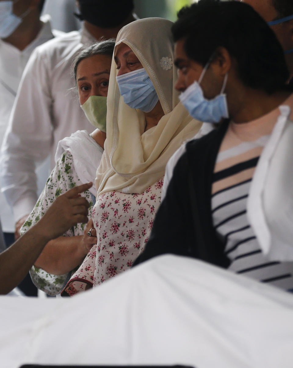 Saira Banu, wife of Indian actor Dilip Kumar, wearing blue mask, center, mourns near his body at a hospital in Mumbai, India, Wednesday, July 7, 2021. Bollywood icon Dilip Kumar, hailed as the “Tragedy King” and one of Hindi cinema's greatest actors, died Wednesday in a Mumbai hospital after a prolonged illness. He was 98. (AP Photo/Rafiq Maqbool)