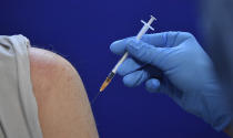 A medical student injects a man at a communally organised vaccination centre in Jena, Germany, Wednesday, Dec. 1, 2021. The city of Jena launched the communal vaccination center on December 1, where people can get vaccinated without an appointment against the coronavirus. (Martin Schutt/dpa via AP)