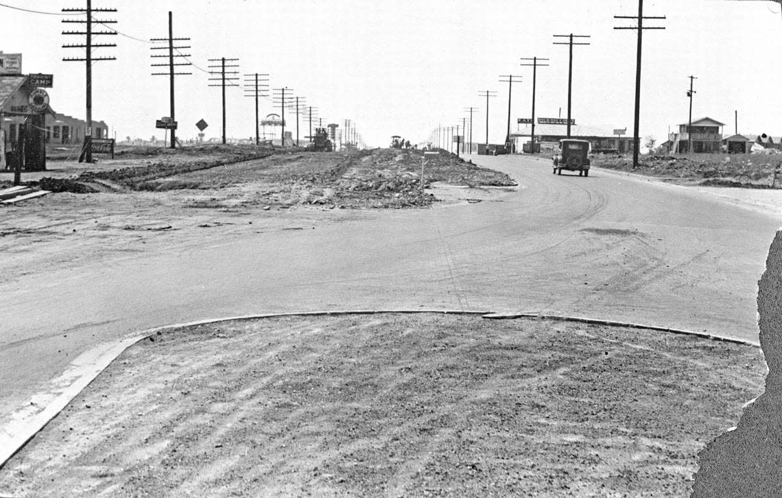 Construction work extending Camp Bowie Boulevard west of the Fort Worth city limits in 1930. Both the Fort Worth Tourist Lodge (near left) and Cottage City (left in the background, with tank on tall framework) are visible, as is the Rockaway Courts & Café on the right.