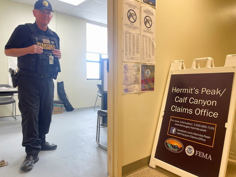 A security guard stands inside a FEMA claims office in More, NM