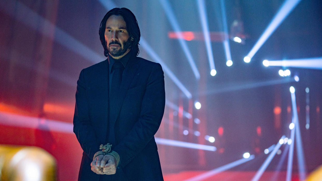  Keanu Reeves as John Wick, with spotlights behind him, in John Wick: Chapter 4. 