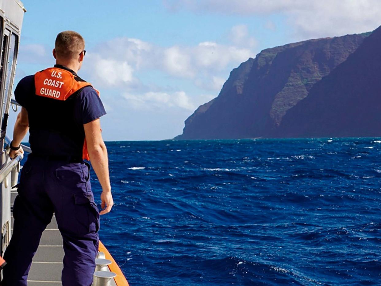 A member of the US Coast Guard Cutter moves toward the Na Pali Coast on the Hawaiian island of Kauai: AP