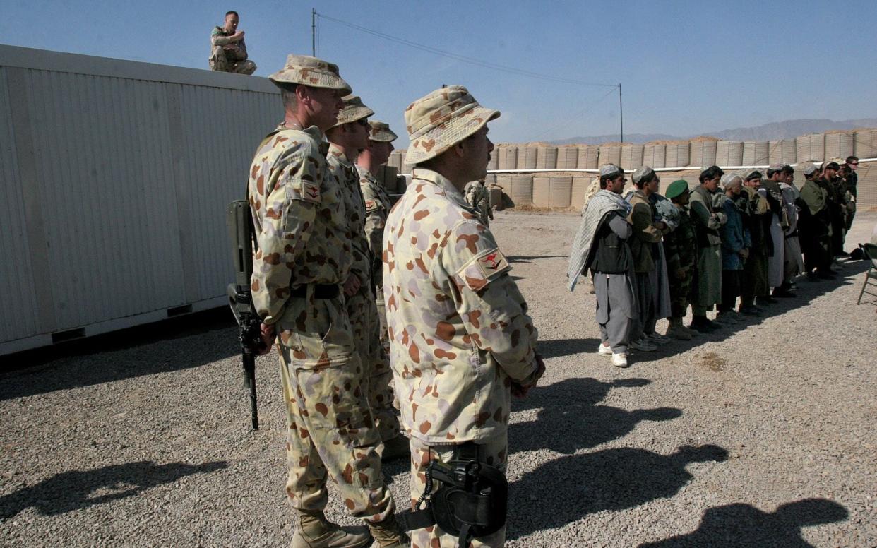 Australian forces stand near locals at the opening of a Trade Training School - AP