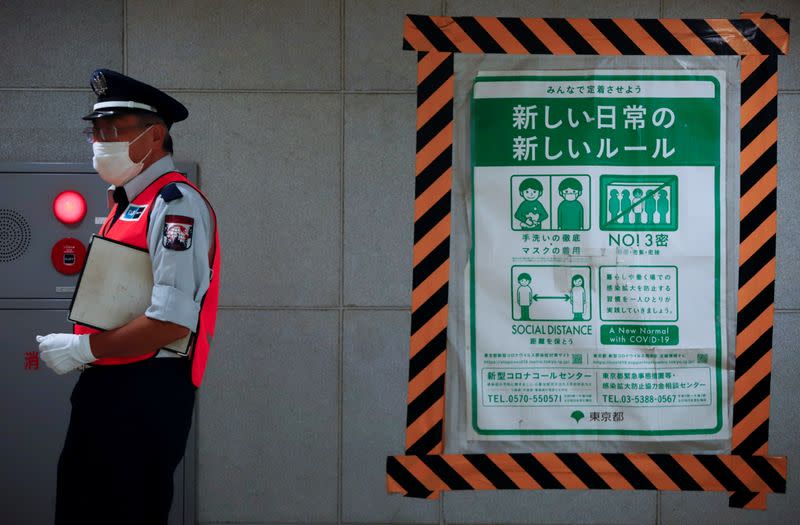 A station employee walks by a COVID-19 infection prevention instructions sign at a Tokyo metro station in Tokyo