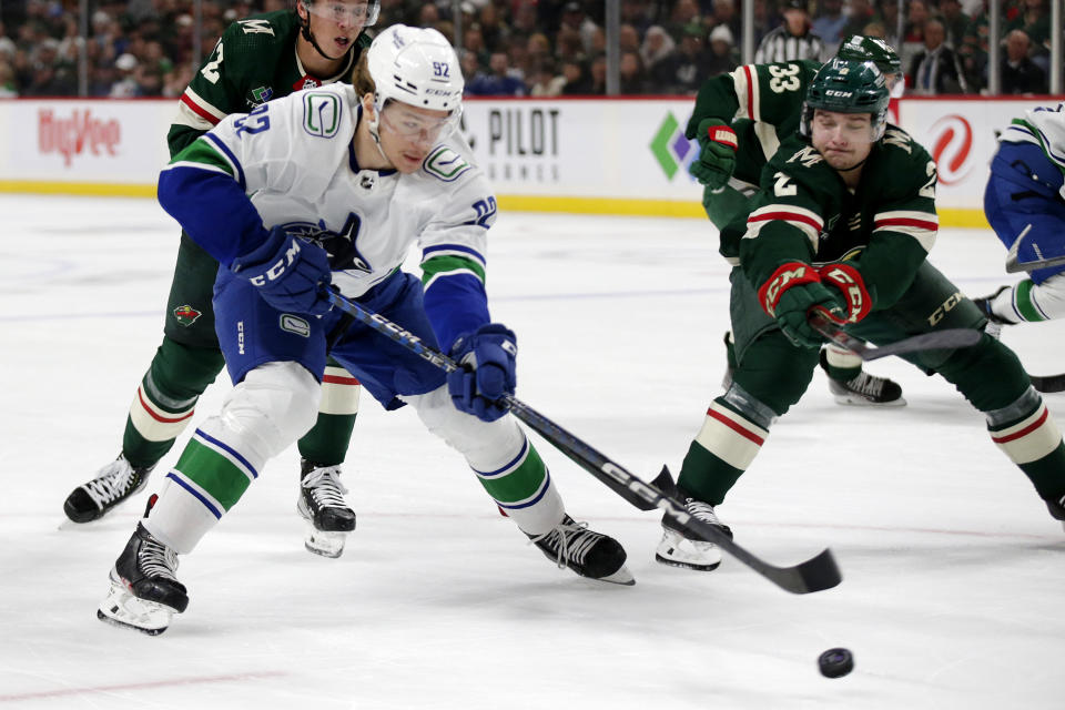 Vancouver Canucks right wing Vasily Podkolzin (92) and Minnesota Wild defenseman Calen Addison (2) compete for the puck during the second period of an NHL hockey game Thursday, Oct. 20, 2022, in St. Paul, Minn. (AP Photo/Andy Clayton-King)