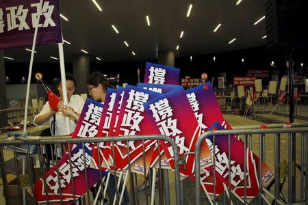 Pro-China supporters dismantle a banner alongside placards which read "support electoral reform", after a rally outside the Legislative Council in Hong Kong, China June 17, 2015. REUTERS/Liau Chung-ren