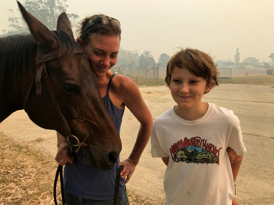 Bec Winter stands next to her son, Riley, while hugging her horse Charmer, who she rode to safety through bushfires on New Year's Eve, in Moruya, Australia January 4, 2020. REUTERS/Jill Gralow     TPX IMAGES OF THE DAY