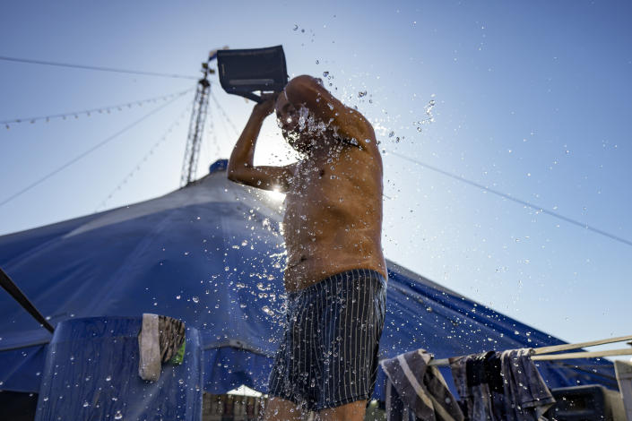 Timoteo Circus performer Alejandro Pavés who plays the role of Alexandra Jean-Marie, takes a bucket shower, on the outskirts of Santiago, Chile, Tuesday, Dec. 20, 2022. Pavés, who comes from a family with a strong military and religious tradition, hid his sexual identity from his family until a television program revealed what he did. His family eventually accepted him but he says there always was the “shame of having a gay son, uncle or cousin.” (AP Photo/Esteban Felix)