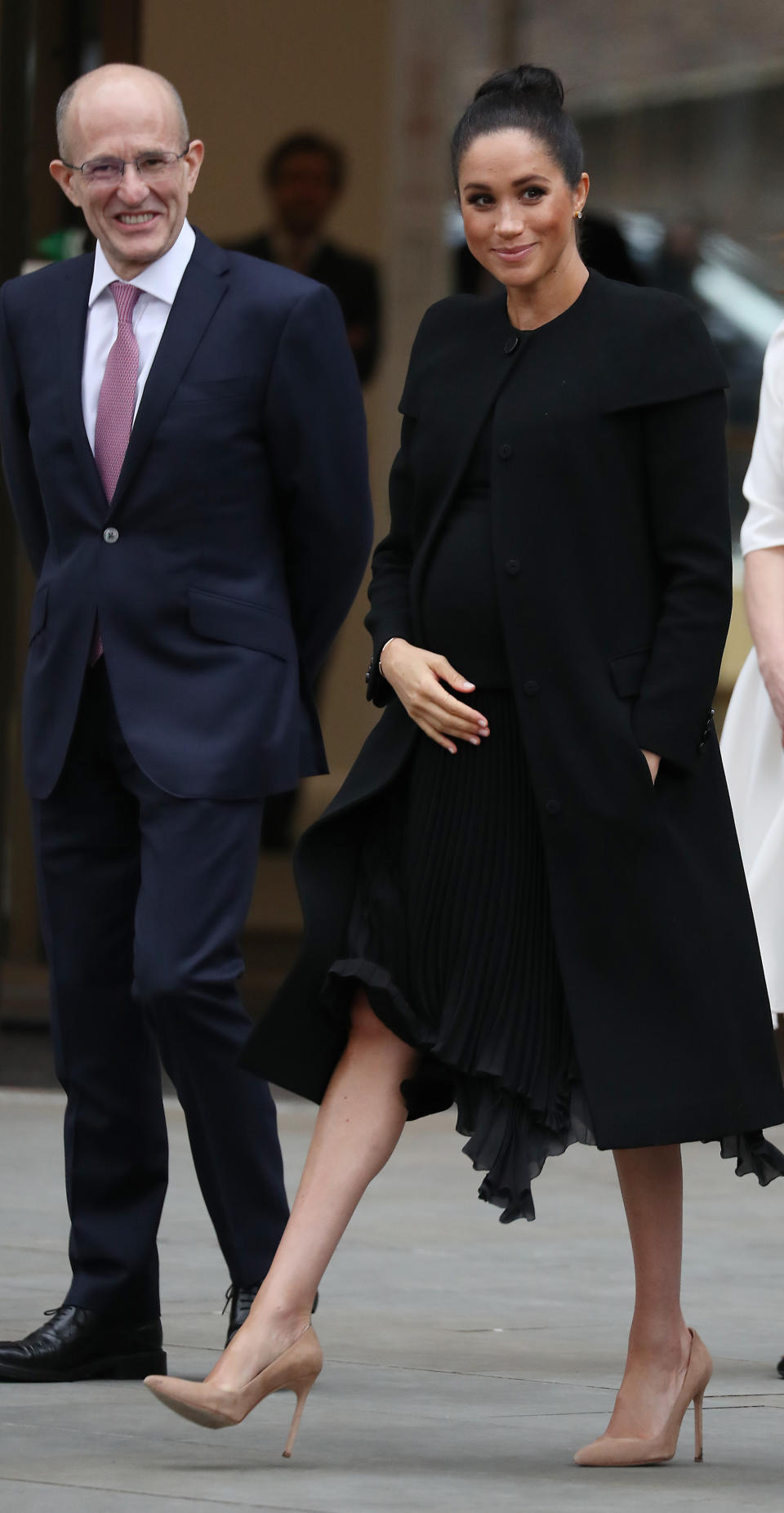 The Duchess of Sussex swapped her trademark messy bun for a slick updo during a trip to the Association of Commonwealth Universities at City, University Of London. She wore a minimal ensemble which included a chic Givenchy coat and matching pleated dress. [Photo: Getty]