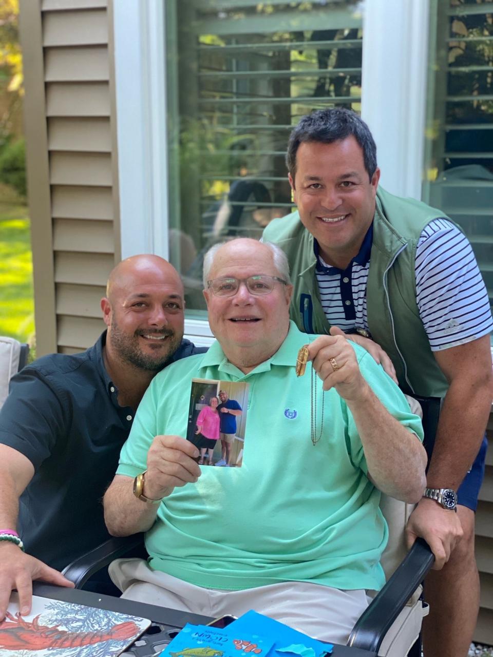 Scott and Brett Steinberg and their dad Jeffery Steinberg holding the dog tag and a photo