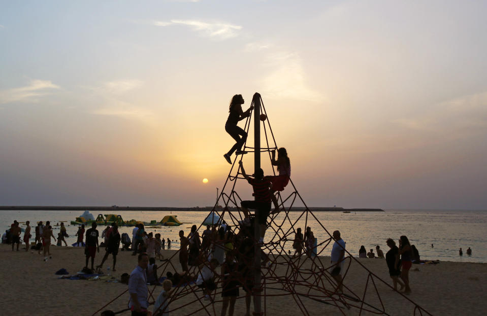 In this Saturday, April 19, 2014, children play on the beach, as the sun sets in Dubai, United Arab Emirates. The ribbon of beach nestled along the towering skyscrapers rising from Dubai’s man-made marina district is a rare spot in the Middle East, bringing together the conservatively dressed and the bikini-clad in a multiethnic mix of those with means and those still striving for a more comfortable life. (AP Photo/Kamran Jebreili)