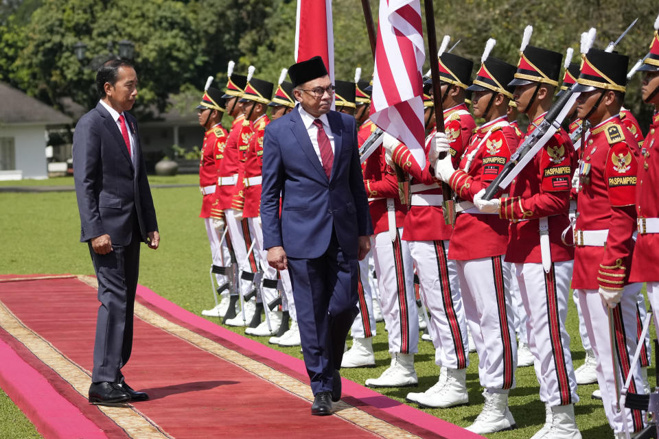 Malaysian Prime Minister Anwar Ibrahim, center, inspects honor guards with Indonesian President Joko Widodo during their meeting at the presidential palace in Bogor, West Java, Indonesia, Monday, Jan. 9, 2023. (AP Photo/Achmad Ibrahim)