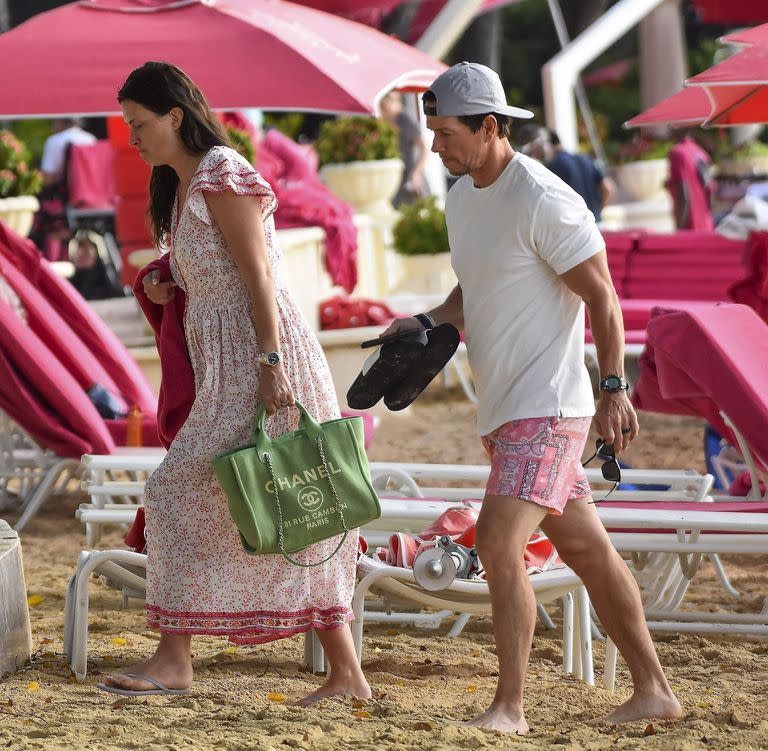 Mientras el actor lució un traje de baño estampado en color rosa, remera blanca y gorra con vicera, Rhea eligió un vestido estampado hasta los tobillos que complementó con un bolso de Chanel 