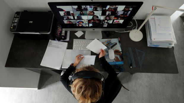 A person sits in front of their home computer using Zoom