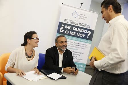 Oscar Hernandez (C), director of the Migration Training Center, welcomes one participant of the forum "I stay or should I go" in Caracas June 28, 2014. REUTERS/Carlos Garcia Rawlins