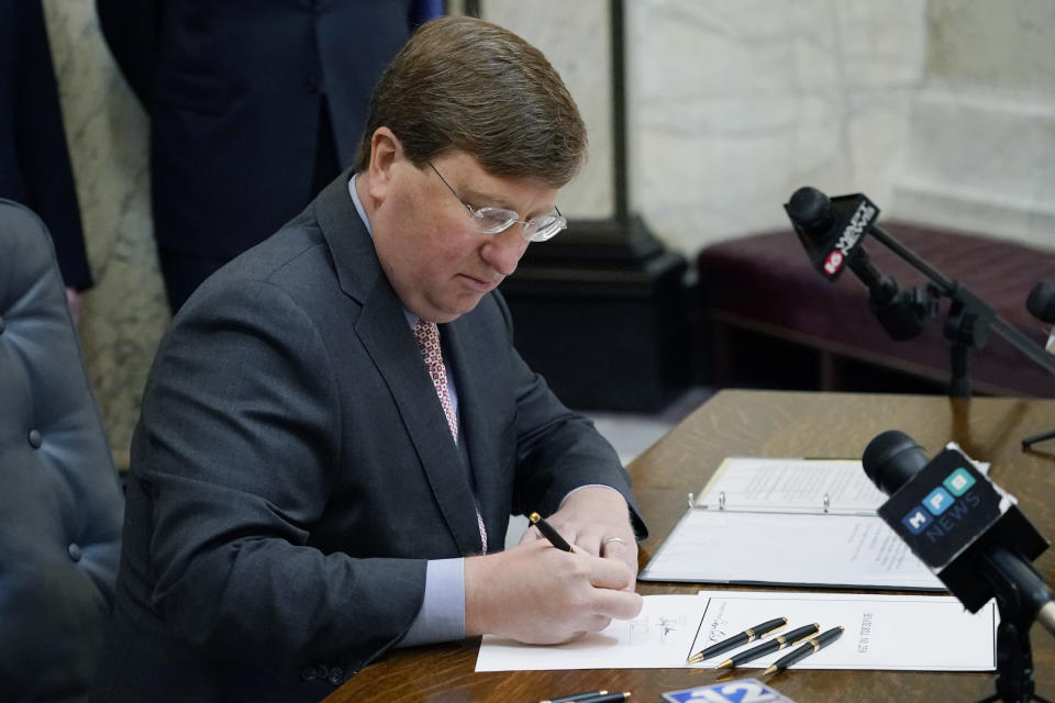 FILE - Mississippi Gov. Tate Reeves signs the first state bill in the U.S. this year to ban transgender athletes from competing on female sports teams at the Capitol in Jackson, Miss., in this Thursday, March 11, 2021, file photo. The NCAA has reached a delicate moment: It must decide whether to punish states that have passed laws limiting the participation of transgender athletes by barring them from hosting its softball and baseball tournaments. (AP Photo/Rogelio V. Solis, File)