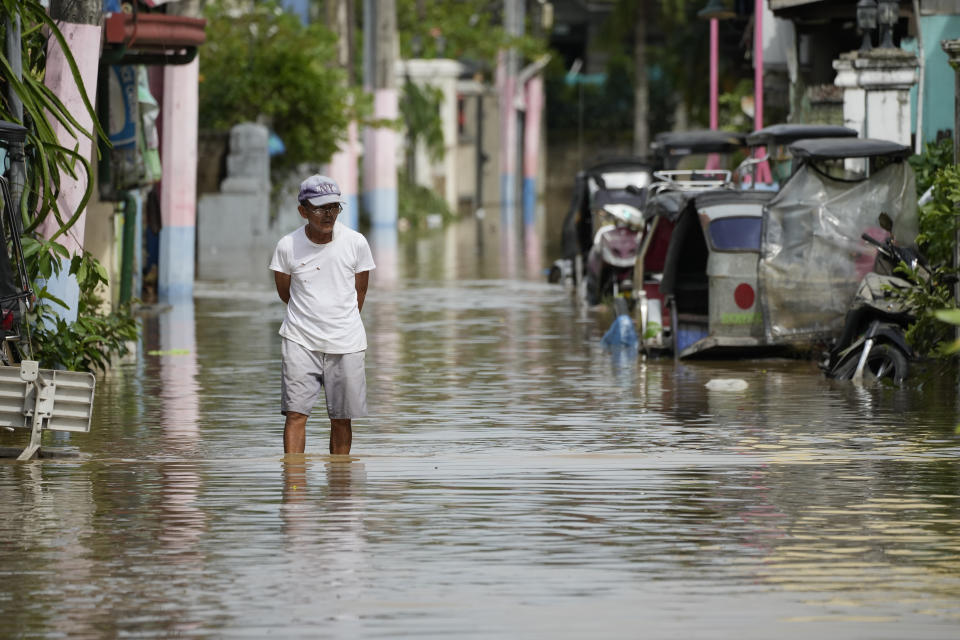 A man walks down a flooded road from Typhoon Noru in San Miguel town, Bulacan province, Philippines, Monday, Sept. 26, 2022. Typhoon Noru blew out of the northern Philippines on Monday, leaving some people dead, causing floods and power outages and forcing officials to suspend classes and government work in the capital and outlying provinces. (AP Photo/Aaron Favila)