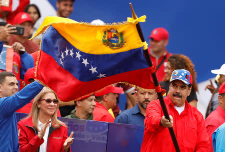 Venezuela's President Nicolas Maduro waives a Venezuelan flag next to his wife Cilia Flores during a rally in support of the government and to commemorate the 20th anniversary of the arrival to the presidency of the late President Hugo Chavez in Caracas, Venezuela February 2, 2019. REUTERS/Manaure Quintero